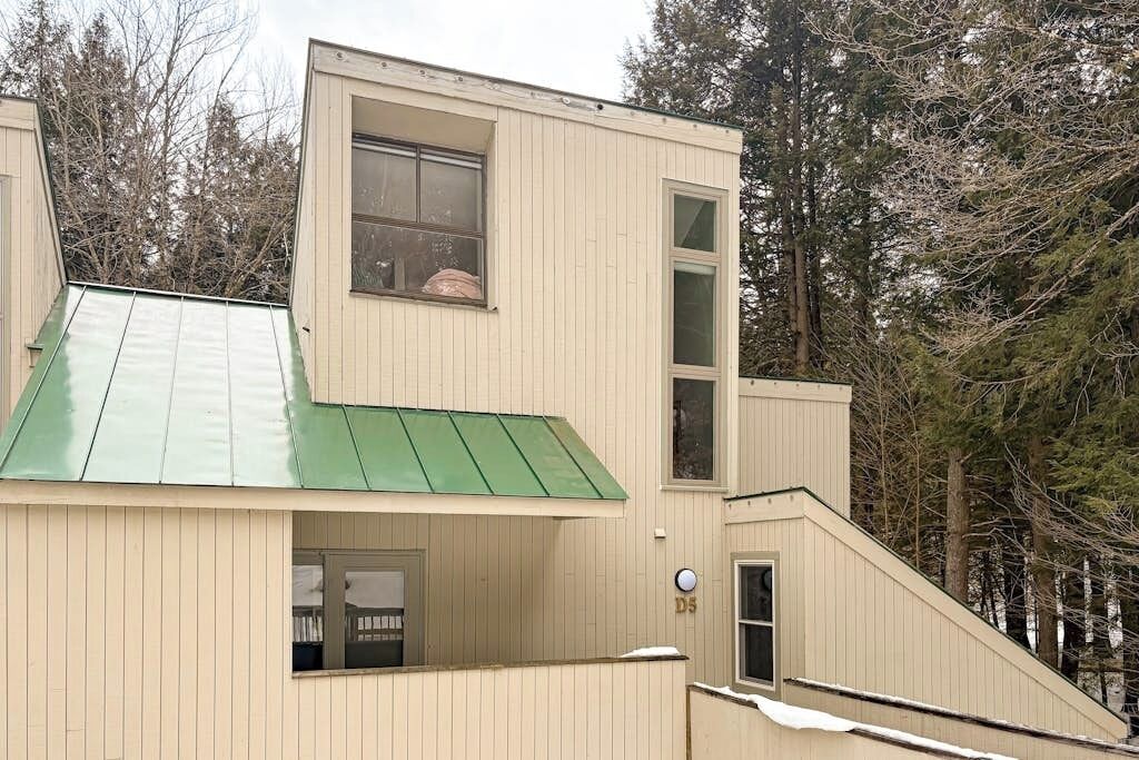 Un bâtiment moderne doté d’un toit en pente, d’une petite entrée et d’une fenêtre.