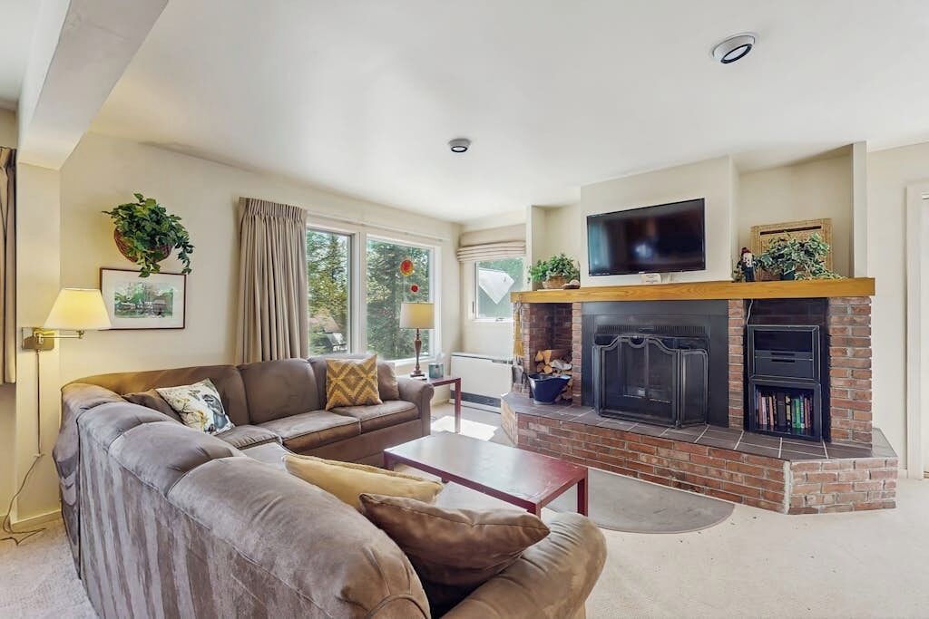 A living room with a fireplace, sofa, and television.