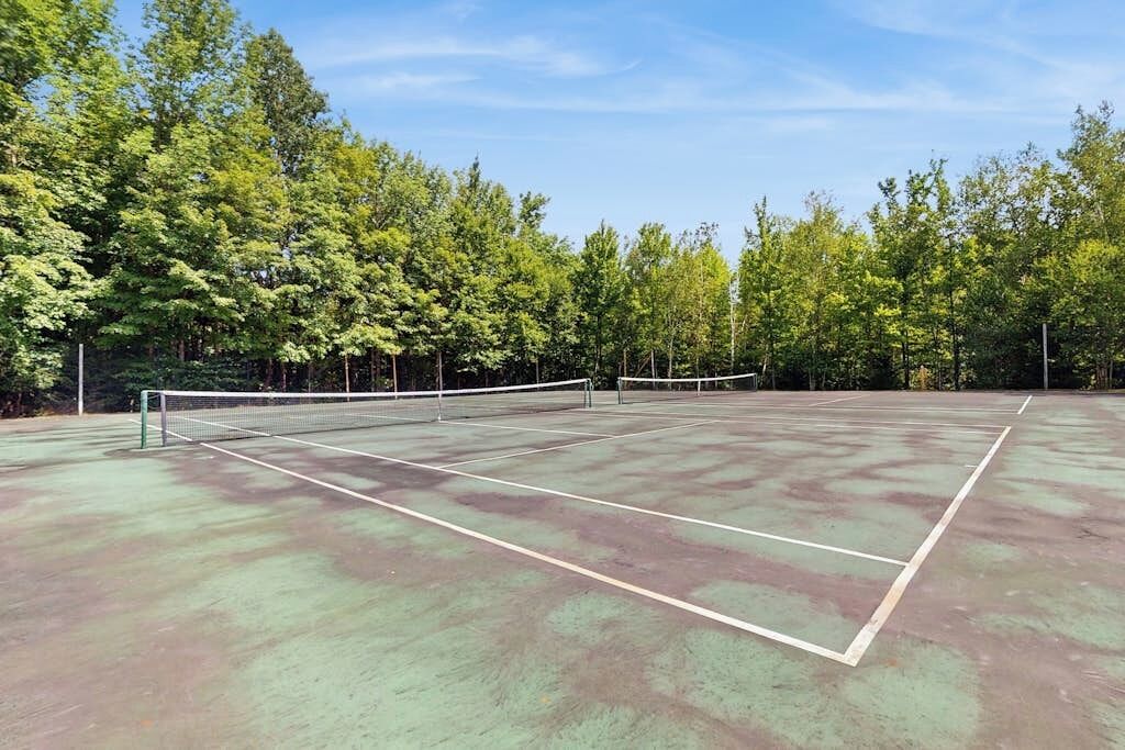 Una cancha de tenis al aire libre rodeada de árboles.