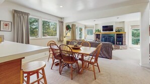 A spacious living area with a dining table, chairs, a sofa, a fireplace, and a television. - Home w/ mountain view, deck, shared pool & tennis, w/d (Warren)
