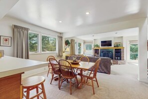 A spacious living area with a dining table, chairs, a sofa, a fireplace, and a television. - Home w/ mountain view, deck, shared pool & tennis, w/d (Warren)