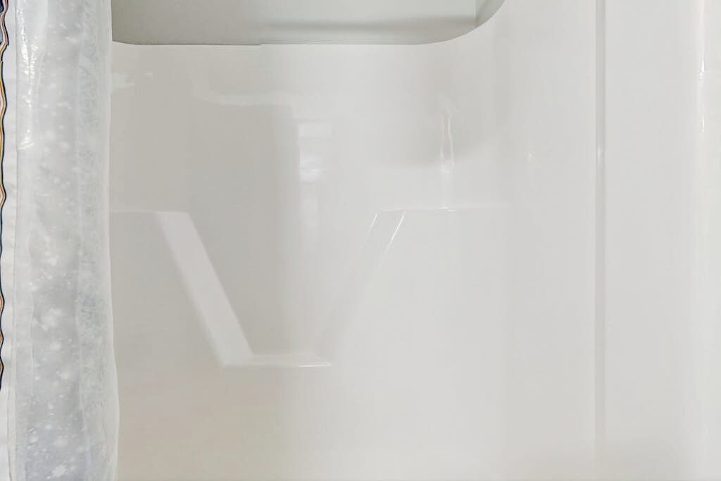 Un baño blanco con una grieta visible en la pared.