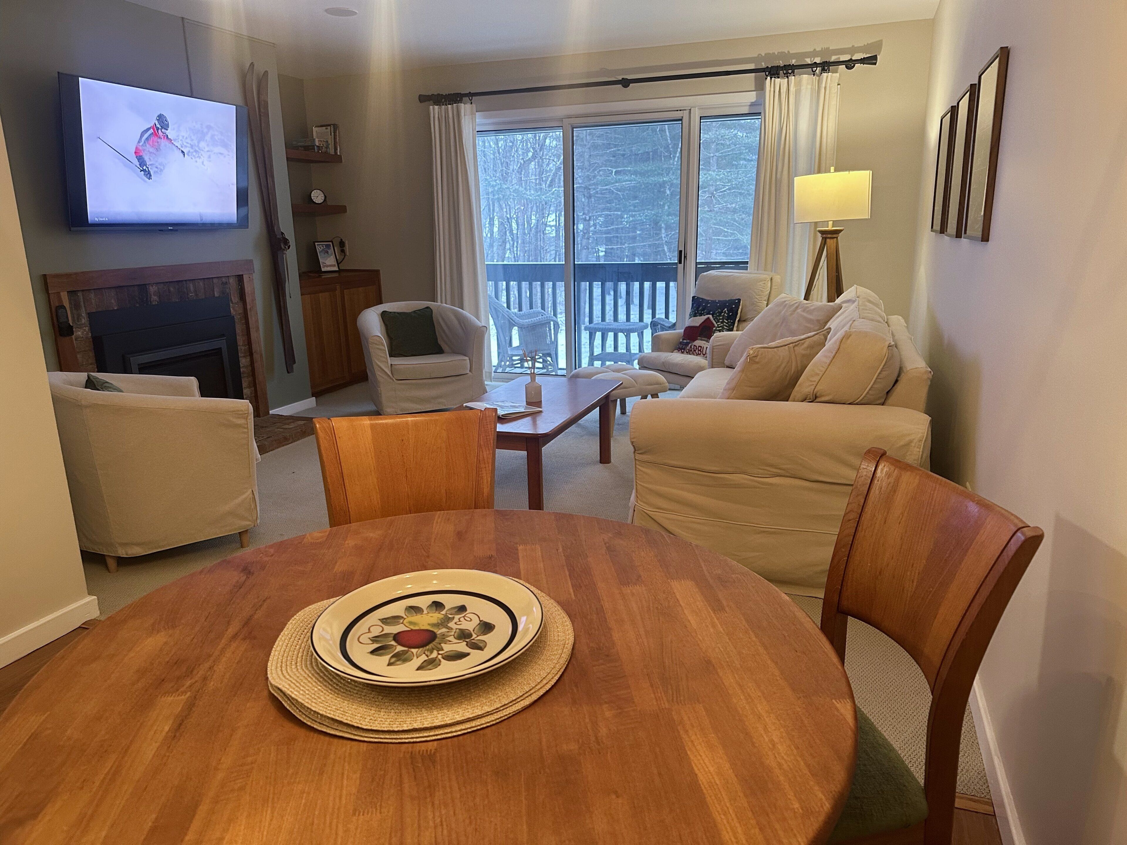 A living room with a television, a fireplace, a dining table with a plate, and a sofa.