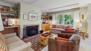Una sala de estar con chimenea, sofá, sillón y una estantería.