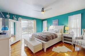 Un dormitorio con cama, mesita de noche, silla, cómoda y ventilador de techo.