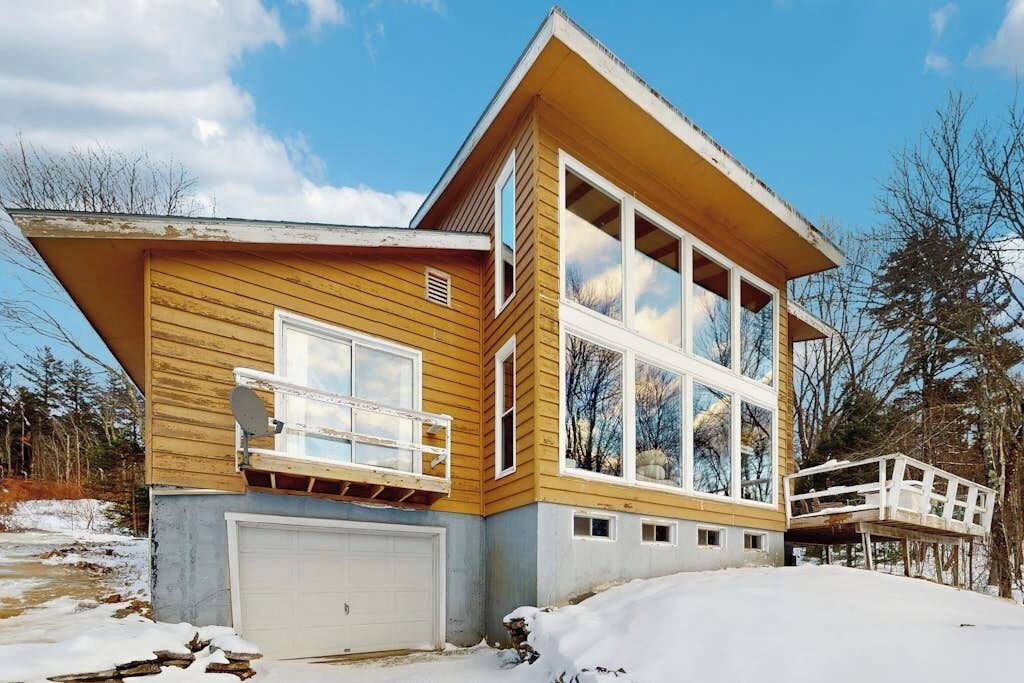 Une maison à deux étages avec un garage, de grandes fenêtres et une terrasse.