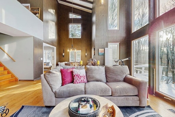 Un salon spacieux avec une grande fenêtre, un escalier et un canapé confortable.