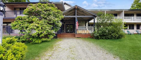 A hotel with a covered entrance, a flag, and a well-maintained lawn.