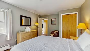 Un dormitorio con una cama grande, un aparador de madera, un espejo, una silla y un armario.