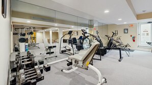 A gym with exercise equipment, mirrors, and a door with an exit sign. - Four Season Condo:  ski, hike, mountain bike & seasonal pool (Warren)