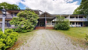 A building with a covered entrance, a flag, and a gravel driveway. - Four Season Condo:  ski, hike, mountain bike & seasonal pool (Warren)