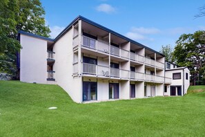 Un immeuble à plusieurs étages, doté de balcons, d’un toit plat et d’une pelouse à l’avant.