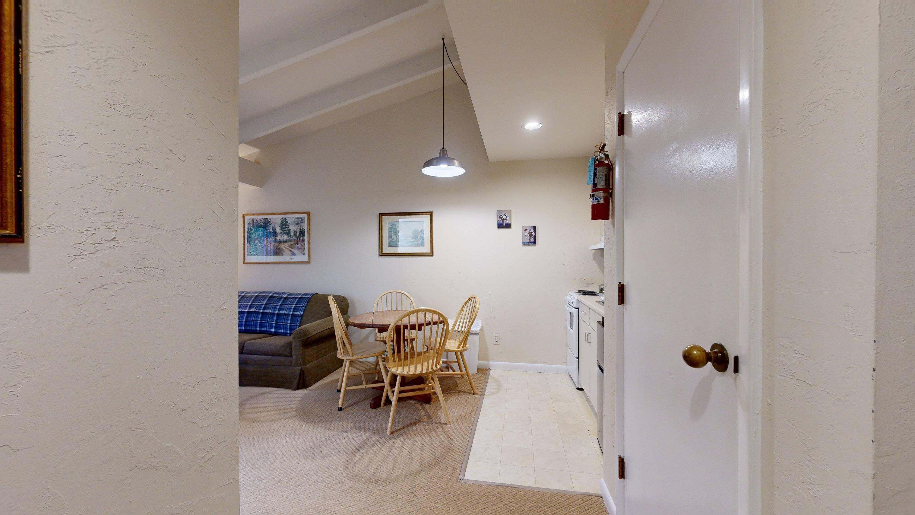 A compact living space with a dining area, a sofa, and a kitchen.