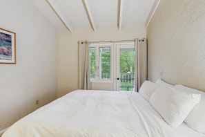 Une chambre à coucher avec un lit, une fenêtre avec des rideaux et une vue sur la verdure.