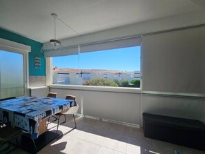 Ein Balkon mit Esstisch, einer Hängelampe und Blick auf Gebäude.