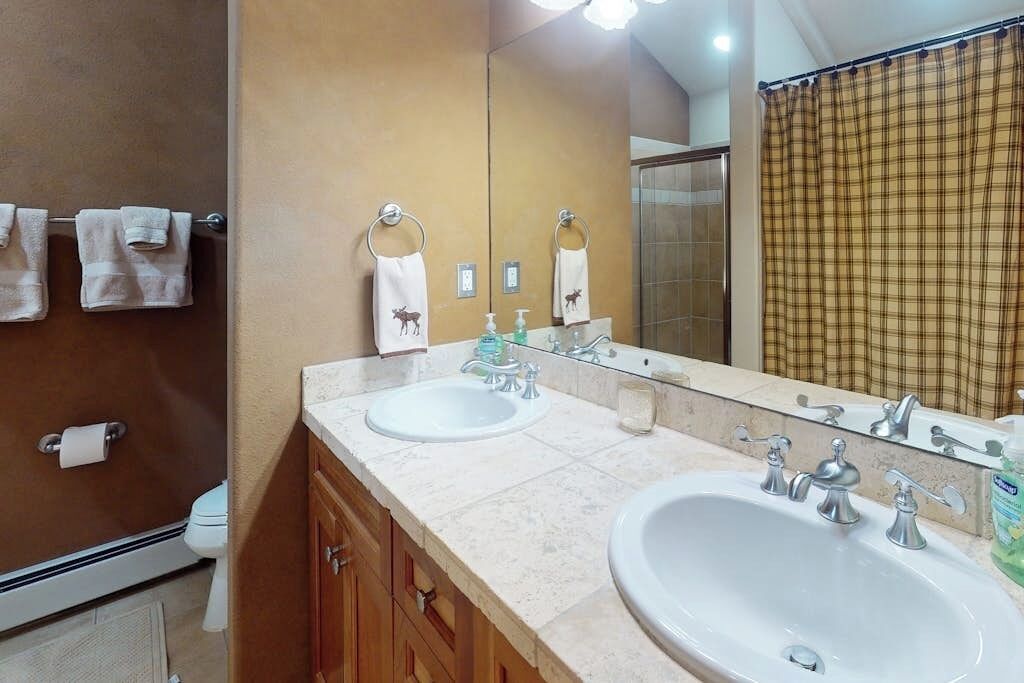 A bathroom with two sinks, a mirror, a towel rack, and a shower curtain.