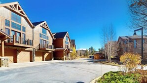 A residential street with modern houses, a clear sky, and a well-maintained road. - Centrally located with balcony, fireplace, heated garage parking & ski locker (Keystone)