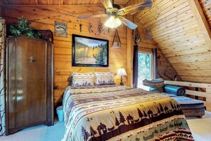 Un dormitorio tipo cabaña de madera con una cama, un armario, un cuadro y un ventilador de techo.