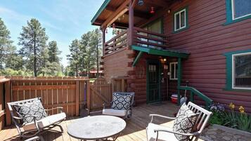 A wooden cabin with a deck, outdoor seating, and a covered porch.
