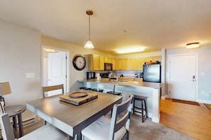 A modern kitchen with a central island, wooden cabinets, a microwave, and a refrigerator. - Mountain resort condo with off-site pool, gym, ski gondola, game room & firepit (Steamboat Springs)