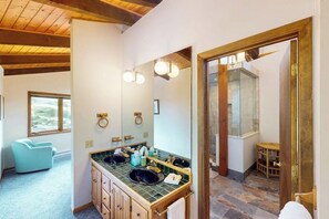 A bathroom with a large mirror, two sinks, a window, and a wooden ceiling. - Conveniently located home with full kitchen, private deck, & loft area (Vail)