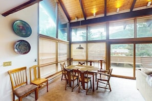 A dining area with a wooden table and chairs, large windows, and a view of the outdoors. - Conveniently located home with full kitchen, private deck, & loft area (Vail)