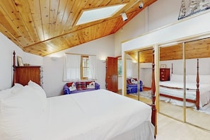 A bedroom with a large bed, a wooden ceiling, a skylight, a wardrobe, and a mirror. - Charming Vail townhome with private deck that is dog-friendly, bus to slopes (Vail)