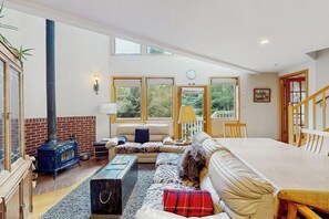 A cozy living room with a fireplace, a sofa, a dining table, and large windows. - Charming Vail townhome with private deck that is dog-friendly, bus to slopes (Vail)