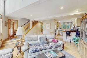 A spacious living area with a sofa, a coffee table, a lamp, and a kitchen in the background. - Charming Vail townhome with private deck that is dog-friendly, bus to slopes (Vail)