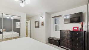 Ein Schlafzimmer mit Bett, Kommode, Fernseher und Spiegel.