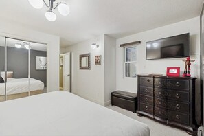 Ein Schlafzimmer mit Bett, Kommode, Fernseher und Spiegel.