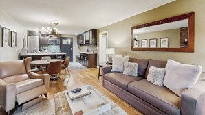 Ein modernes Wohnzimmer mit einer Couch, Sesseln, einem Couchtisch und einem Essbereich mit Stühlen und Tisch.