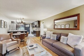Ein modernes Wohnzimmer mit einer Couch, Sesseln, einem Couchtisch und einem Essbereich mit Stühlen und Tisch.