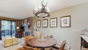 Ein Essbereich mit einem runden Tisch, Ledersesseln, einer Kristallleuchter, gerahmten Bildern an der Wand und einem Kamin aus Backsteinen.