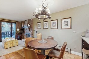 Ein Essbereich mit einem runden Tisch, Ledersesseln, einer Kristallleuchter, gerahmten Bildern an der Wand und einem Kamin aus Backsteinen.