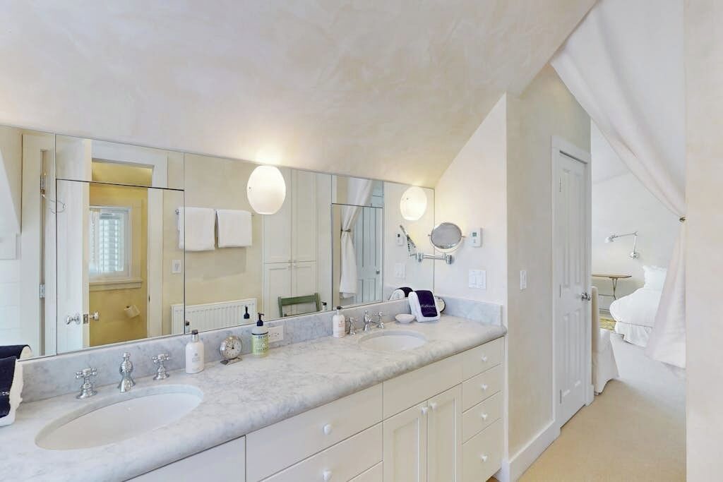 A bathroom with two sinks, a large mirror, and a towel rack.