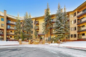 A multi-story hotel with balconies, a central entrance, and snow-covered trees. - Charming condo w/ full kitchen, shared pool & hot tub - near ski resort (Vail)