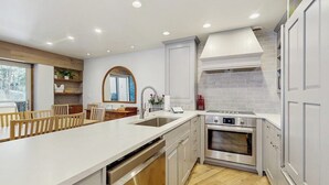 Een moderne keuken met een centraal eiland, roestvrijstalen apparatuur en uitzicht op de omgeving.