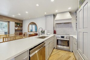 A modern kitchen with a central island, stainless steel appliances, and a view of the outdoors. - Charming condo w/ full kitchen, shared pool & hot tub - near ski resort (Vail)