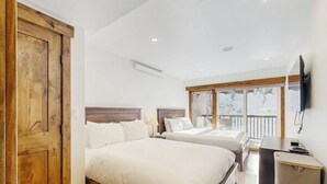 Een slaapkamer met twee bedden, een houten garderobe, een bureau en een televisie.
