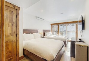 A bedroom with two beds, a wooden wardrobe, a desk, and a TV. - Charming condo w/ full kitchen, shared pool & hot tub - near ski resort (Vail)
