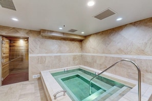 A spa area with a rectangular hot tub, a shower area, and a tiled wall. - Conveniently located condo w/ fast wifi, shared hot tub & amazing location (Vail)