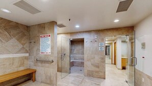 Uma área de spa com um banco, uma porta de vidro e um aviso com as regras do spa.