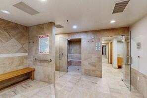 A spa area with a bench, a glass door, and a sign listing spa rules. - Conveniently located condo w/ fast wifi, shared hot tub & amazing location (Vail)