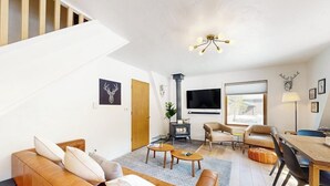 A modern living room with a sofa, coffee table, and a fireplace. - Tranquil riverside cabin with mountain views and easy access to Breckenridge (Blue River)