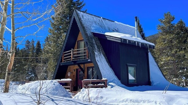 A cabin with a sloped roof, a balcony, and a wooden deck. - Tranquil riverside cabin with mountain views and easy access to Breckenridge (Blue River)