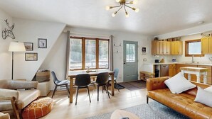 A cozy living room with a sofa, a coffee table, and a dining area with chairs and a table. - Tranquil riverside cabin with mountain views and easy access to Breckenridge (Blue River)