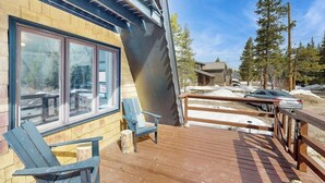A wooden deck with two chairs, a building with large windows, and a snowy landscape. - Tranquil riverside cabin with mountain views and easy access to Breckenridge (Blue River)