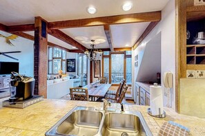Una cocina con una isla grande, vigas de madera y un comedor con vistas.