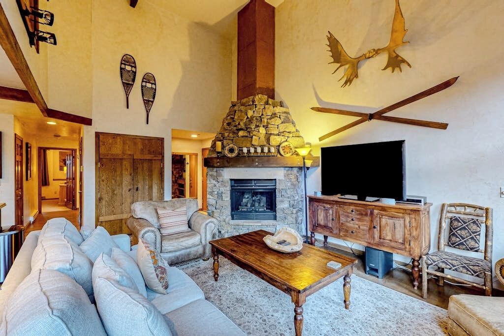 Un salon chaleureux avec une cheminée en pierre, un téléviseur et un meuble en bois.
